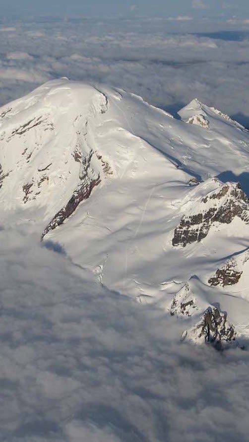 The summit of Mount Baker sticking out of the clouds in Washington State