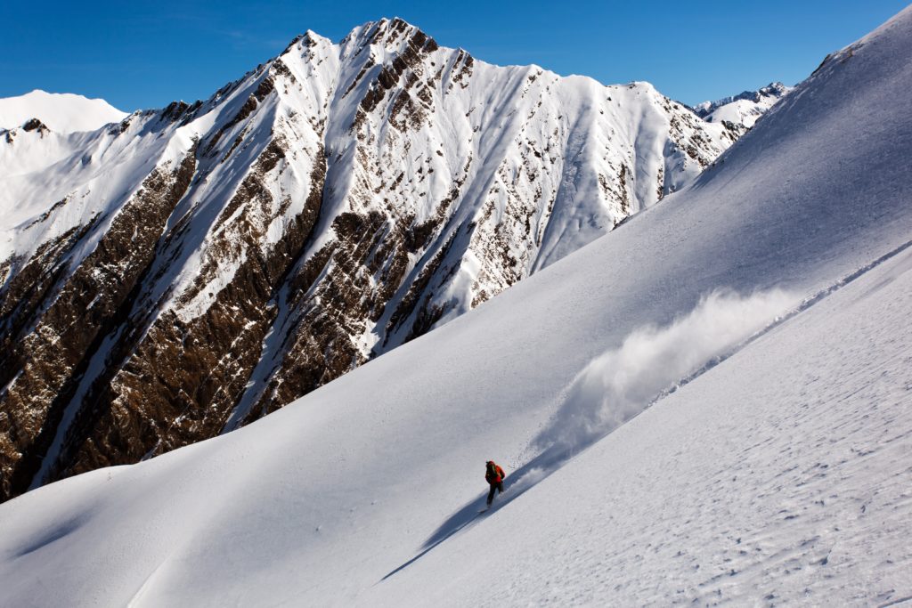 Enjoying the perfect powder turn down Schmirntal while ski touring in Austria with the Italian Border in the background