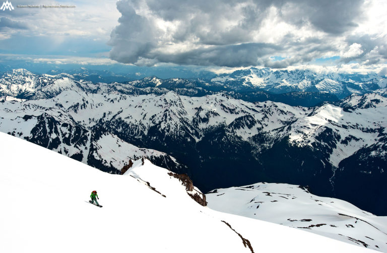 Riding down the Sitkum Glacier on Glacier Peak with the North Cascades in the background during the Suiattle Traverse