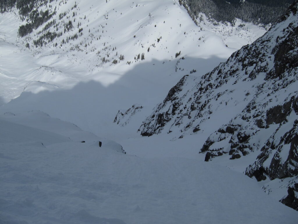 Traversing above a cliff with the Northwest couloir on Mount Shuksan Below
