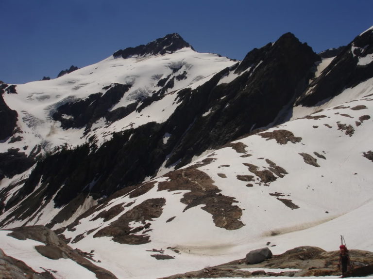 Jason climbing the moraine of the Pilz Glacier with Clark Mountain in the distance on day 3 of the Dakobed Traverse