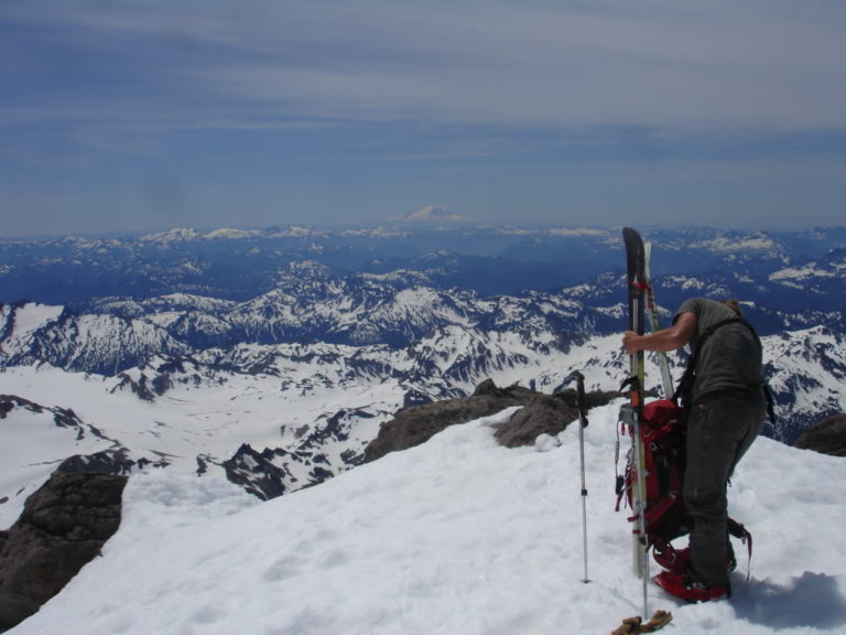 Standing on the summit of Glacier Peak with Mount Rainier in the distance