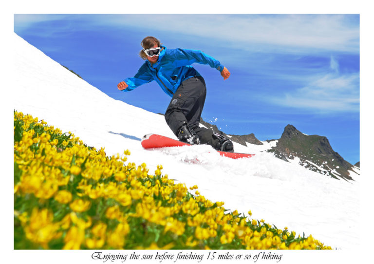 Snowboarding a strip of snow next to the spring flowers as we exit the Dakobed Traverse