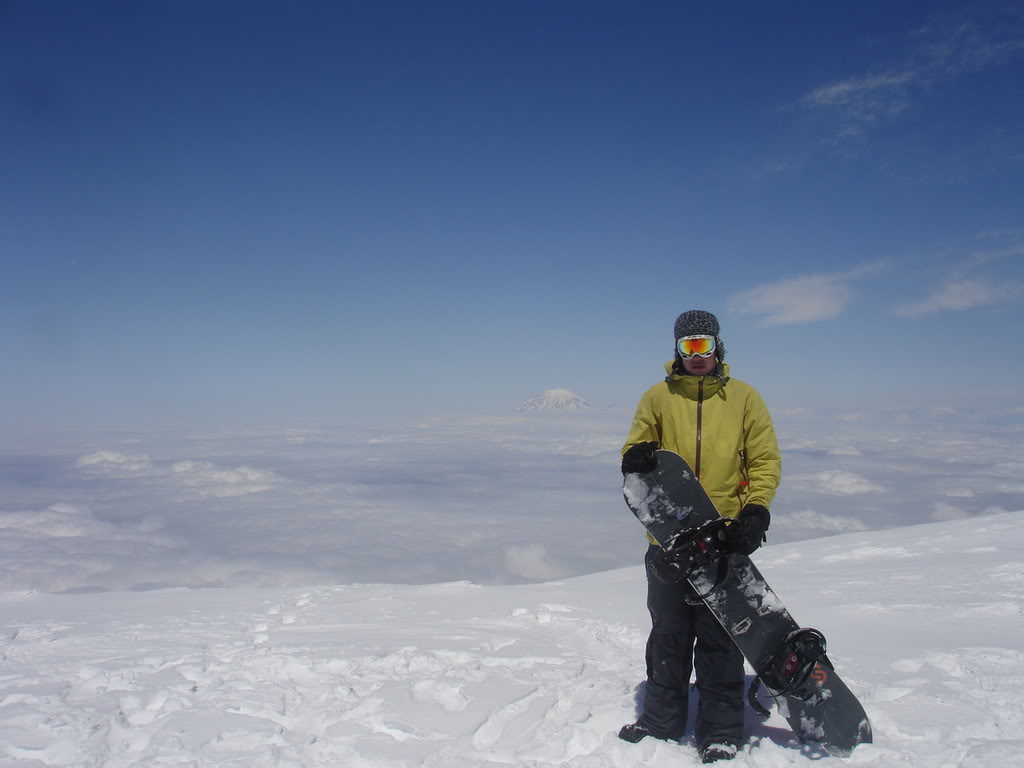 Standing on the summit of Mount Adams and preparing to snowboard the Southwest Chutes with Mount Rainier in the distance