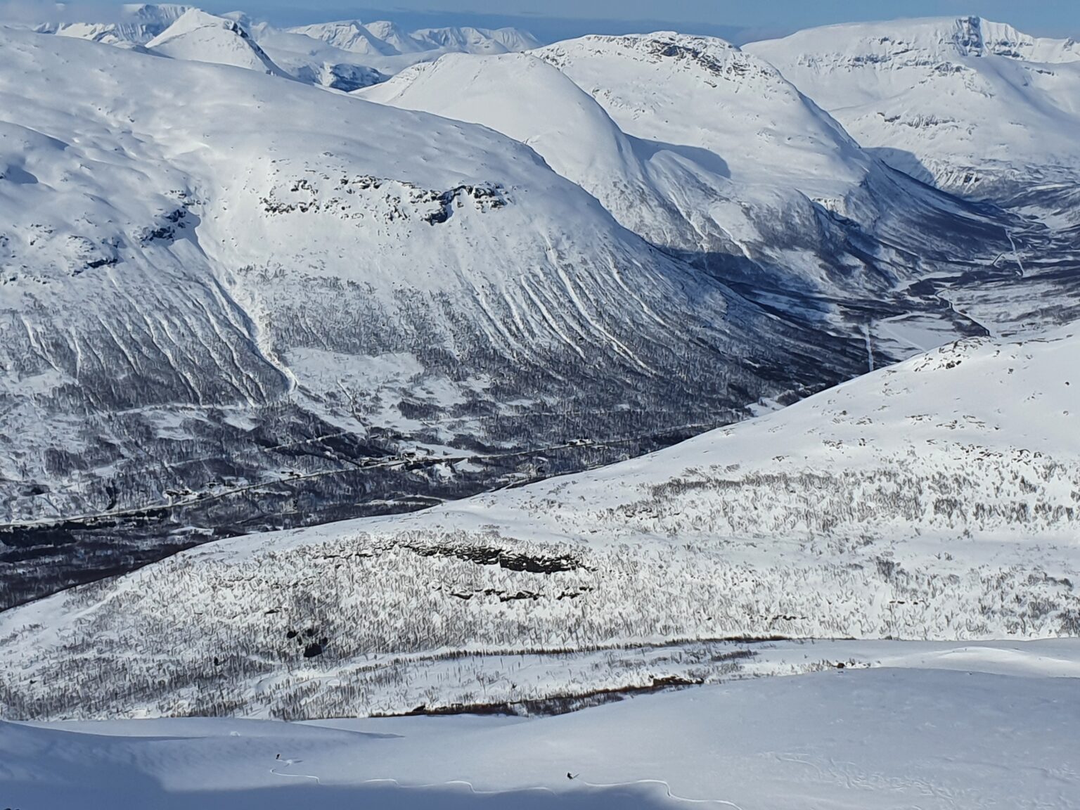 Two tracks snowboarding down Istinden Ridge with the Tamokdalen Backcountry in the Distance