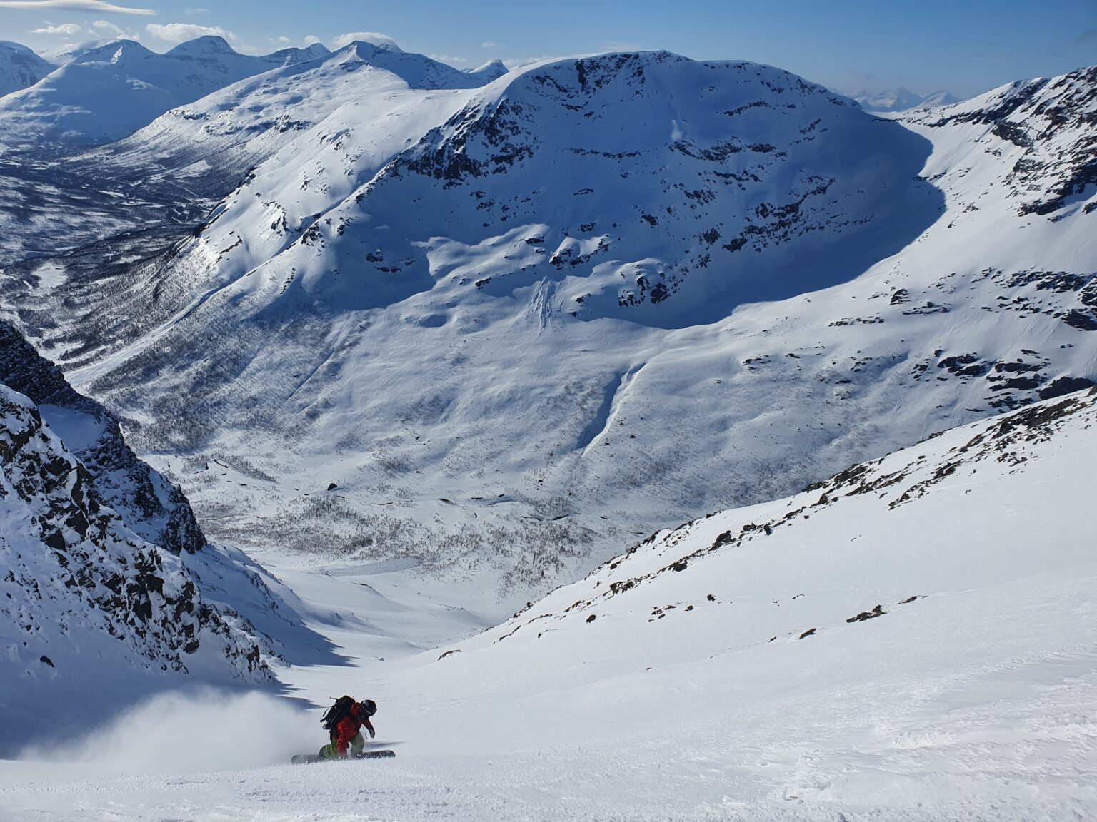 Jukkis snowboarding down Cahcevahnjunni with Tamokfjellet in the background