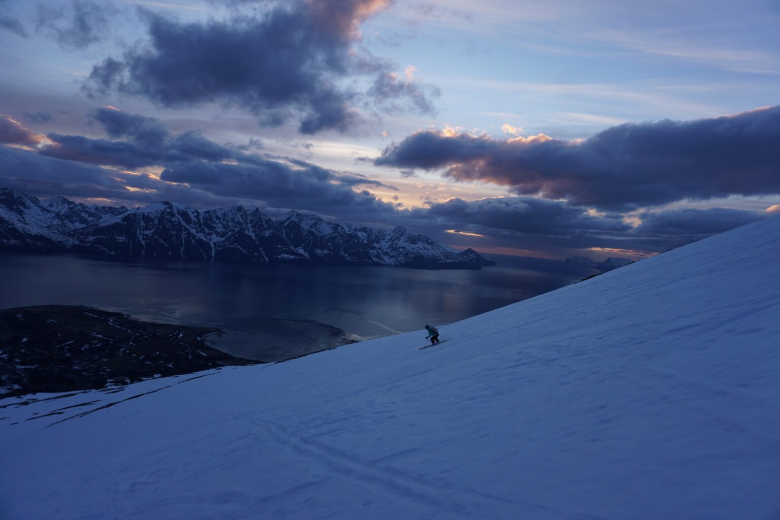 Skiing down the final slopes of Storhaugen with the sun setting in the distance