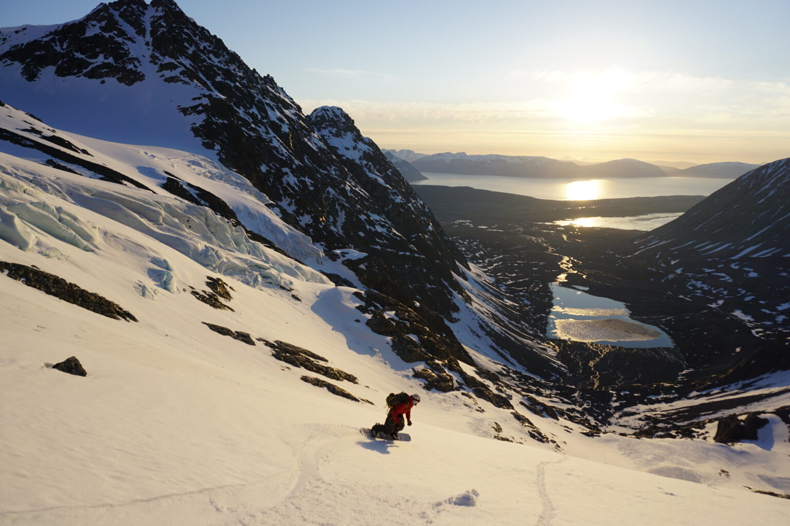 Snowboarding down the the Lenangsbreen Glacier in the Lyngen Alps of Norway with the Midnight sun in the background