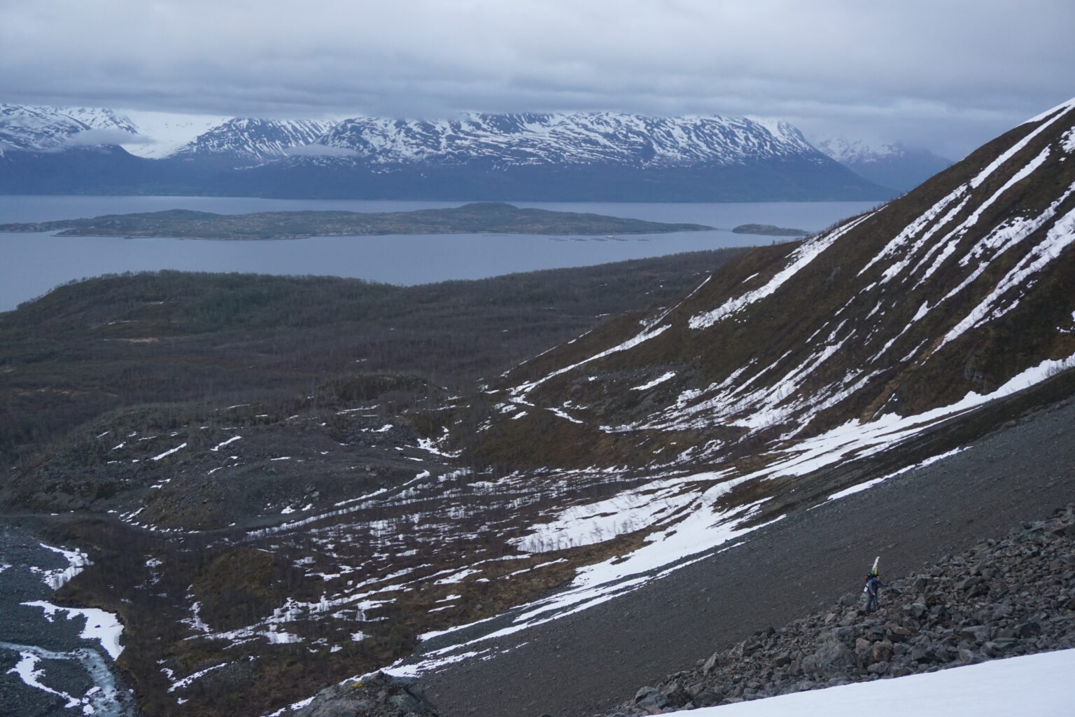 Hiking up a scree field with Lyngen fjord in the distance
