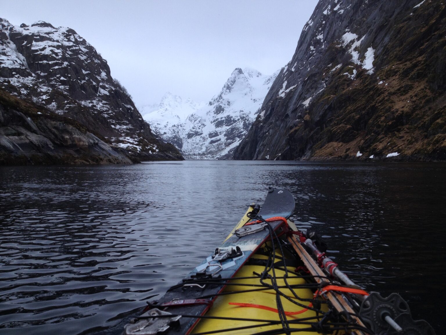 Kayaking into the Trollfjord with a snowboard in the Lofoten Islands of Norway