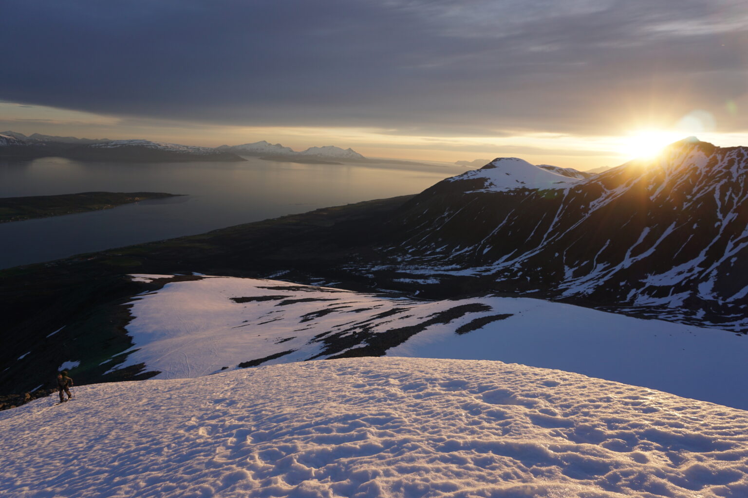 Sun setting being the mountains to the north while Ben ski tours up Veidalsfjellet