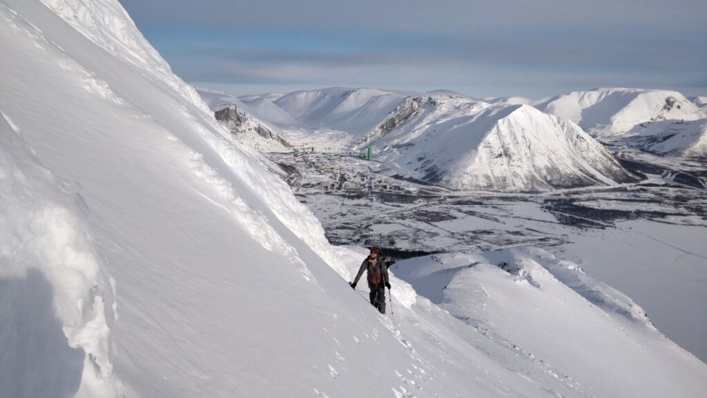 Ski touring up a mountain with Kirovsk in the background