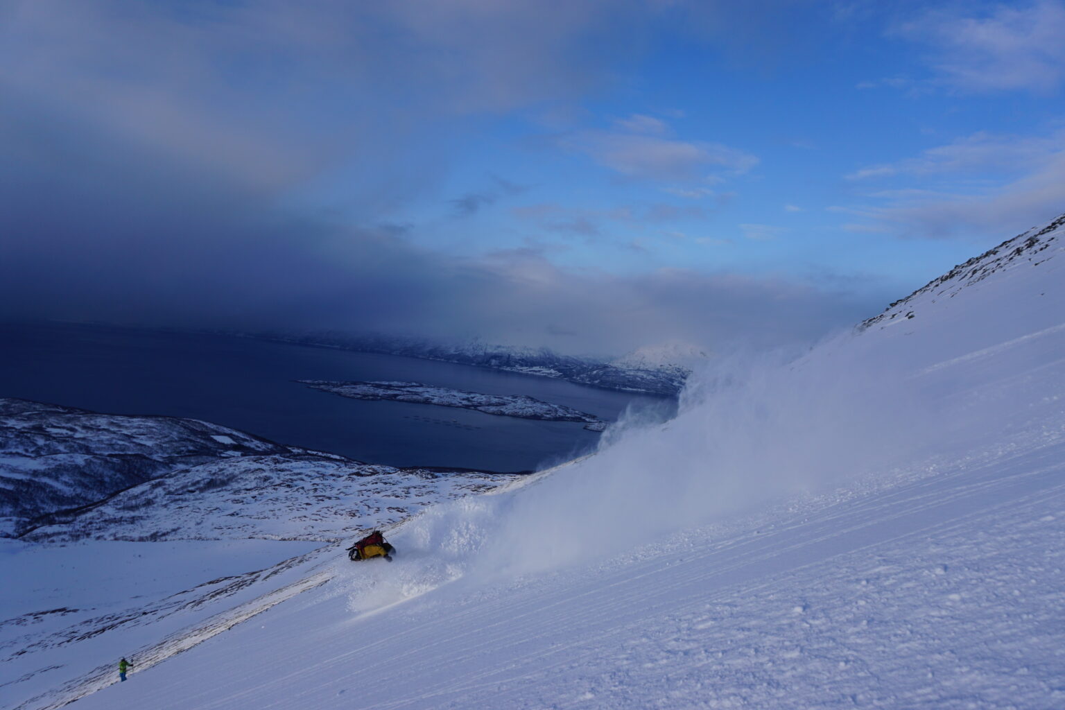 Snowboarding with the Lyngenfjord in the distance during the Lyngen Alps Traverse