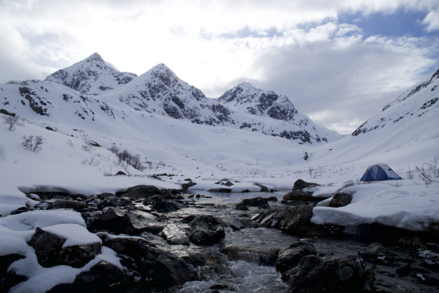 Arriving at a stream after snowboarding down while on the Lyngen Alps Traverse