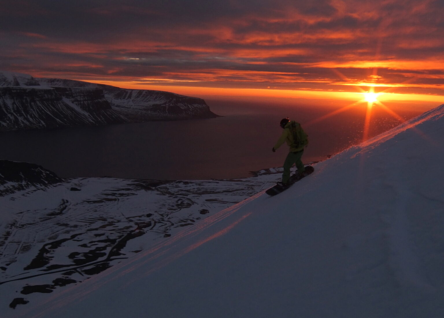 Snowboarding down to the sunset alpenglow in the Dýrafjörður area of the Westfjords of Iceland